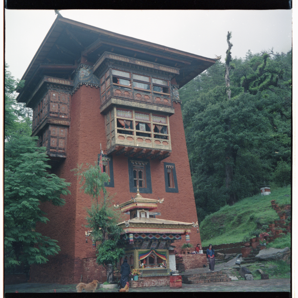 The Utse of Dechenphug, a tall earthen red tower rising from the green hill