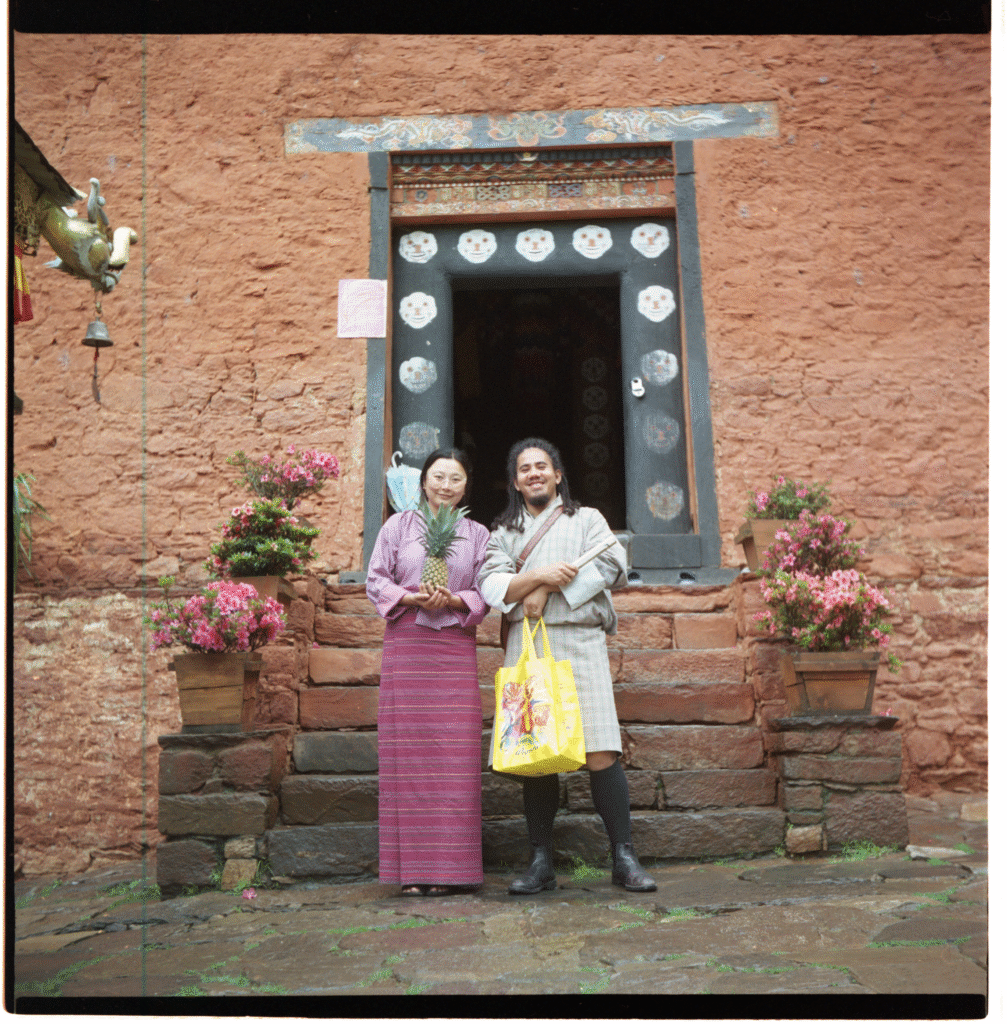 Wang and Yangday pose in their traditional clothes before the temple entrance, holding offerings of fresh fruit