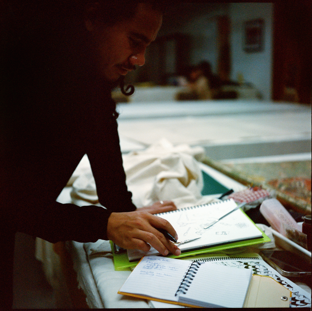 Wang leans over to sketch tools laid out on a table