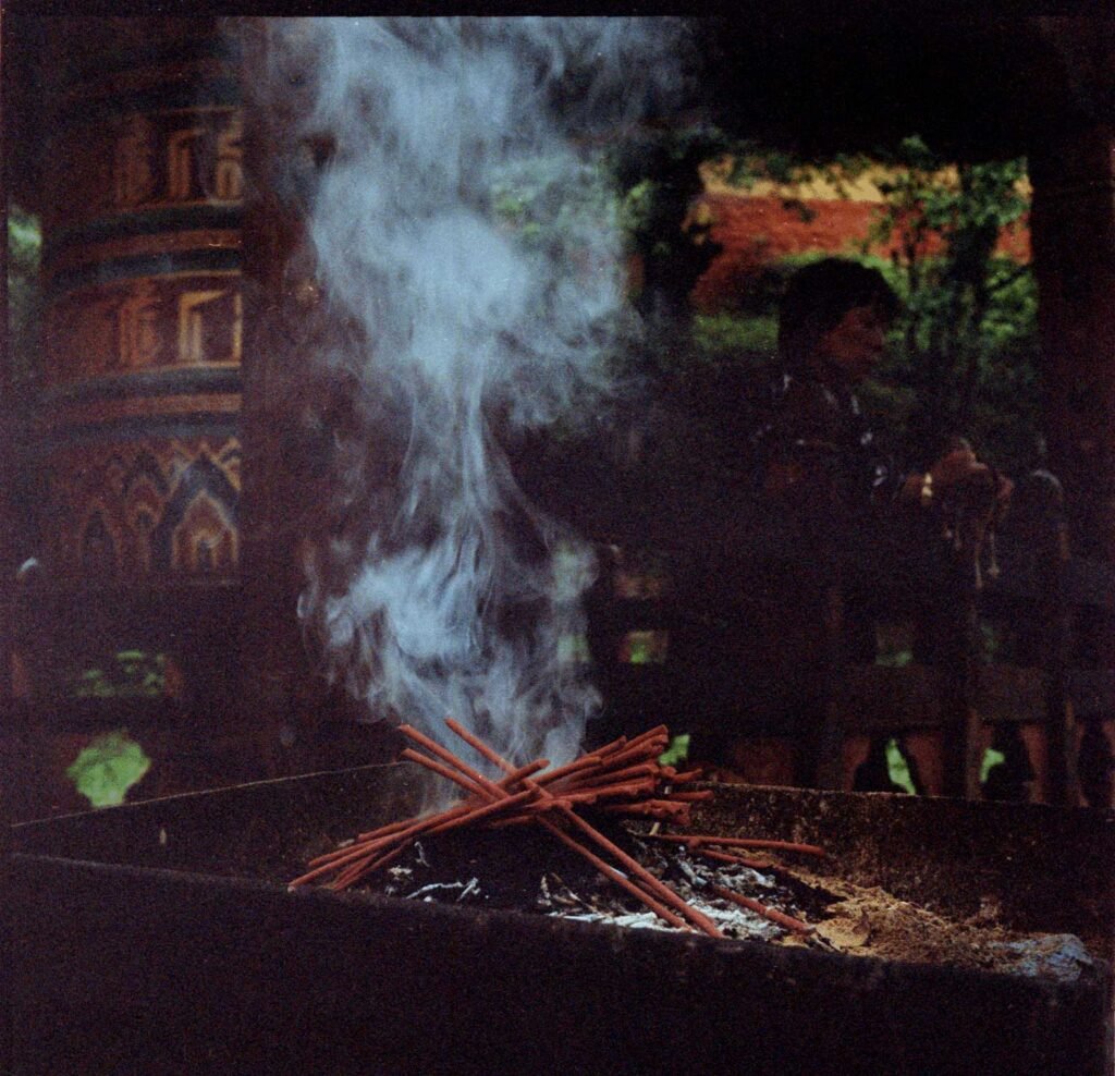A smoke offering rises from incense in front of a large prayer wheel