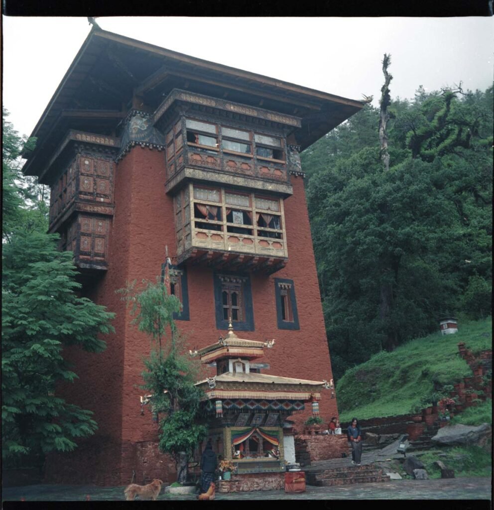 The Utse of Dechenphug, a tall earthen red tower rising from the green hill