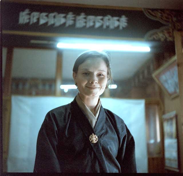 2025June18_Thimphu_Y_KP800_NLAB_Tierney02-scaled Tierney is a white woman wearing a green kira inside the National Library