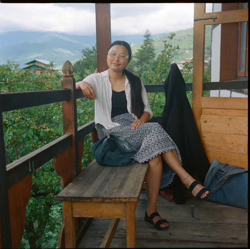 25June26_Thimphu_Y_KPortra800_-6_DfT_YangdayLa Yangday is in her 30s and perches on a bench overlooking a tree in Thimphu